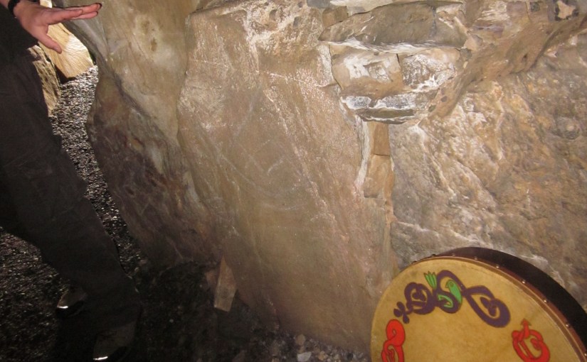 Photo of part of the inside the Four Knocks tomb, Ireland, showing a drum and person's legs.